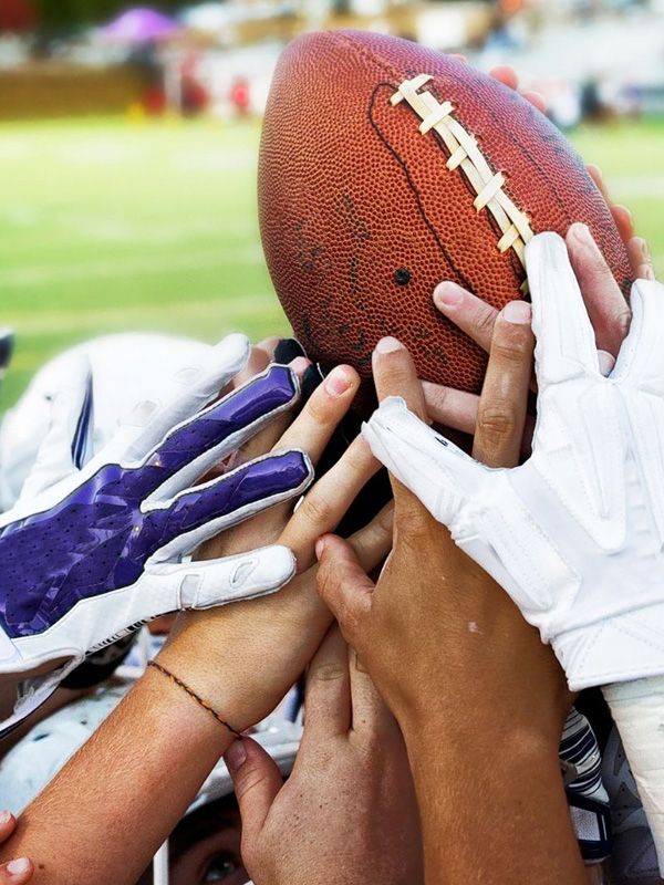 many hands raising a football