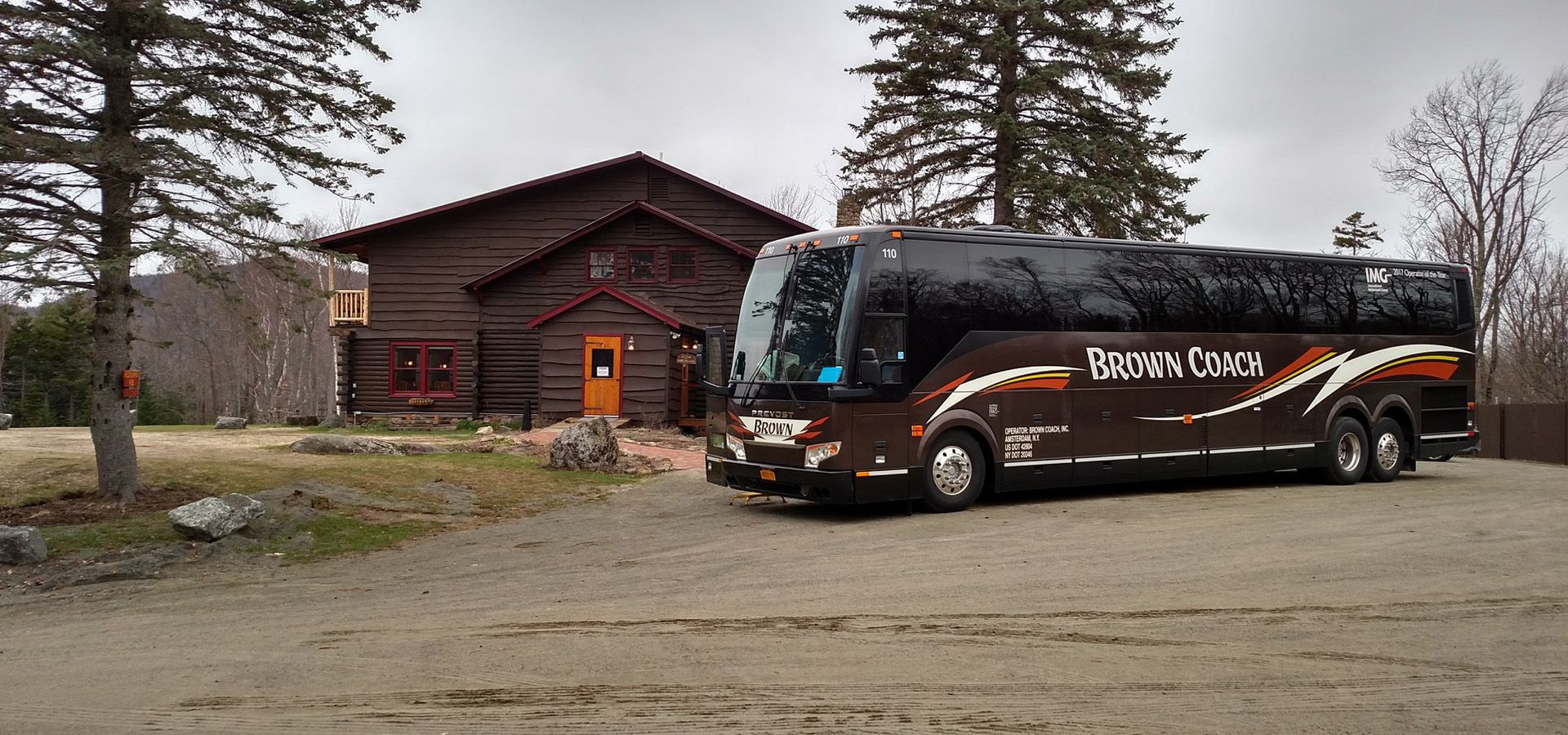 Brown Coach bus parked in front of a cabin